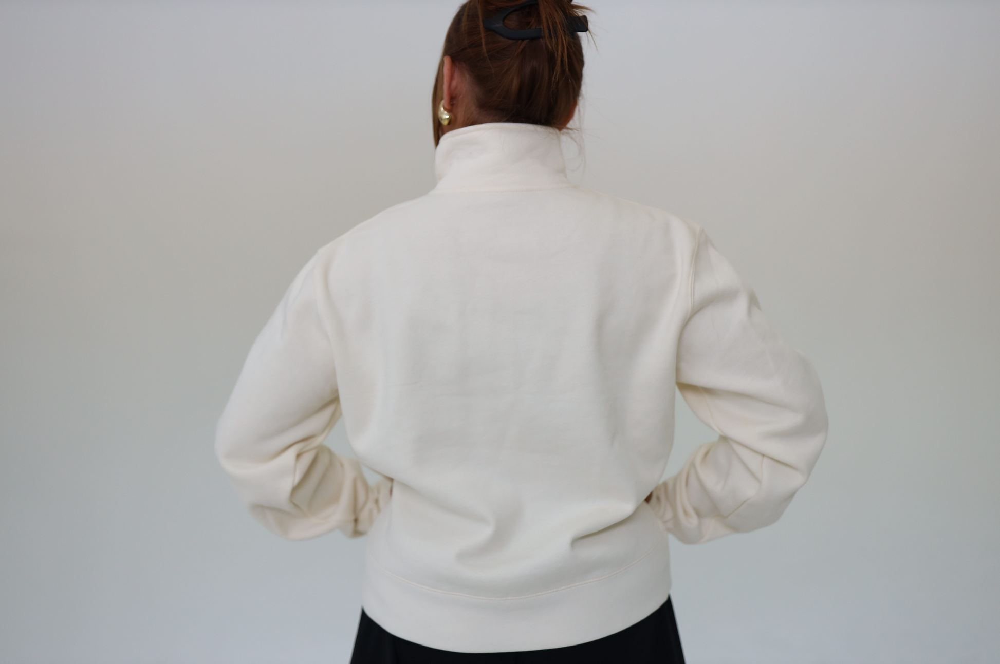 Person wearing a cream mock neck sweater against a plain background